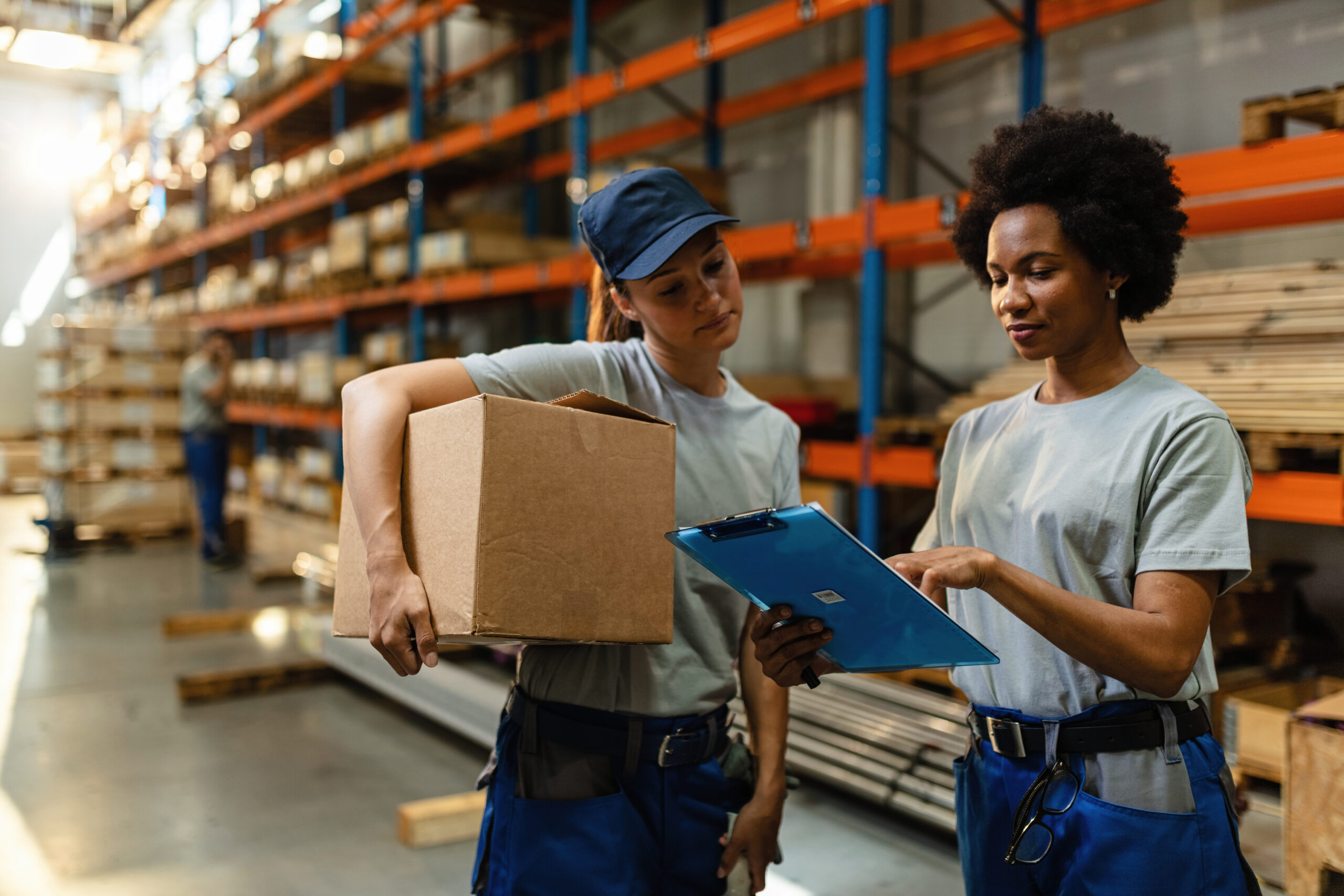 African American worker and her coworker reading order list before the shipment while working in a warehouse.